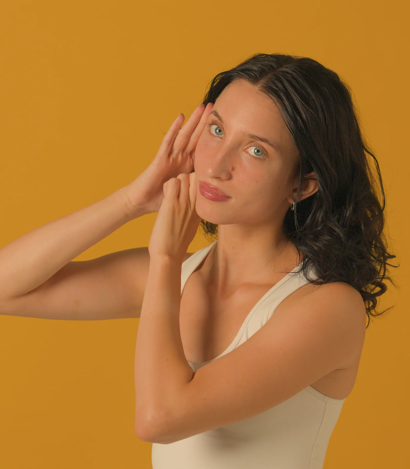 A woman resting her fingertips along her temple and her knuckles under her cheekbone during a facial lymphatic drainage massage